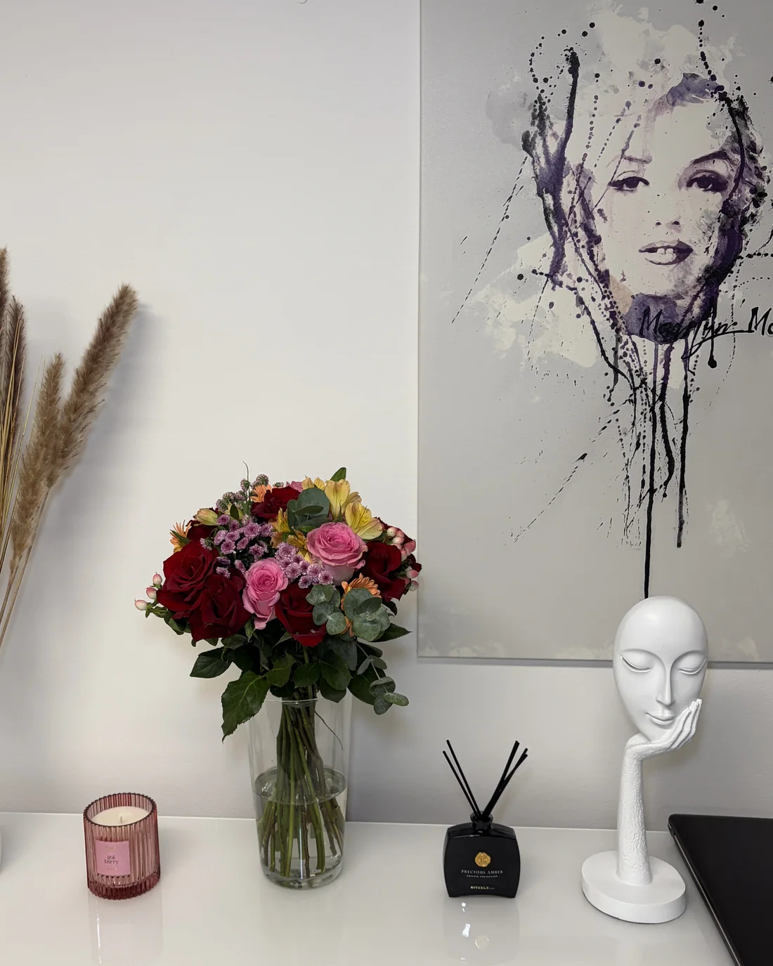 Blick ins Studio: Blumenstrauß, Trockengräser und Wandbild vor weißer Wand